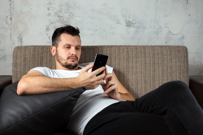 Create meme: the man on the couch, A man on the couch with a phone, a man is sitting on the sofa