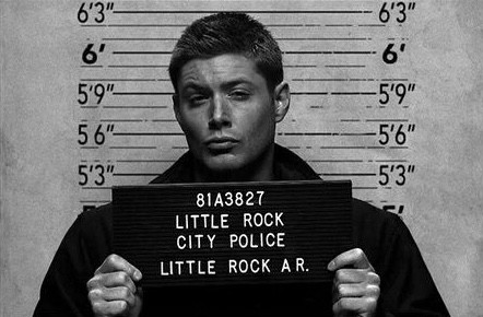 Create meme: Dean Winchester is in jail, dean winchester , Dean Winchester with a sign in prison