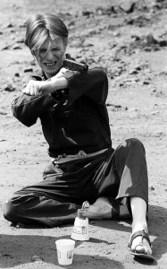 Создать мем: david bowie молодой фотосессия с пистолетом, молодой дэвид боуи улыбка, дэвид боуи фотосессии 1975